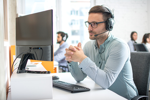 Customer service support operator man with headphones and microphone listening to his client in call center