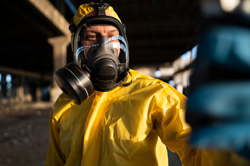 Portrait of a man in protective workwear examining radioactive ruined building.