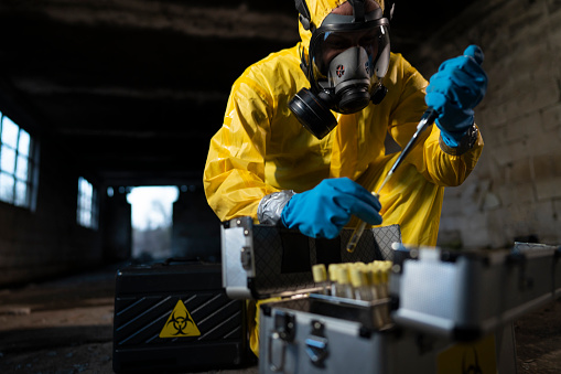Man in protective workwear taking toxic samples at the  radioactive ruined building.