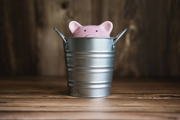 Piggy Bank Sinking Inside Steel Bucket stock photo