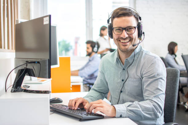 istock Male customer support phone operator with headset working in call centre. Group of sales agent working in office. 1212984680