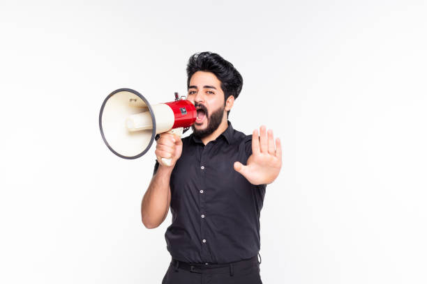 istock Portrait of young man handsome shouting using megaphone over white background 1212991417