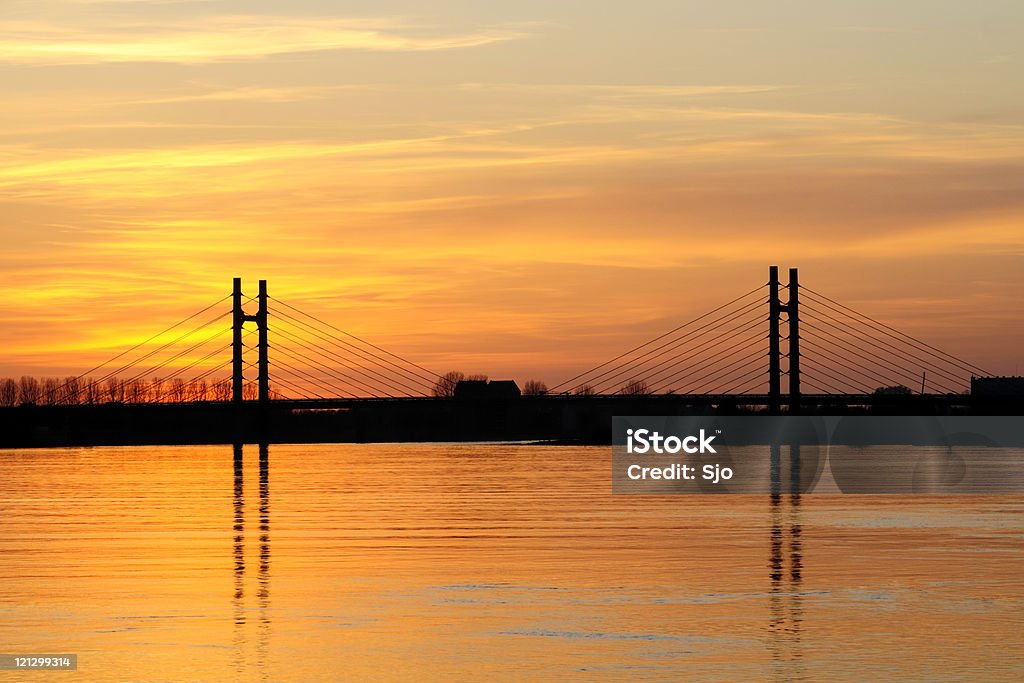 Sunset at the river Sunset over the river IJssel with in the background the Molenbrug, a suspension bridge near the town of Kampen in The Netherlands. Architecture Stock Photo