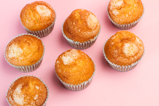 Vanilla and sugar cupcakes on a pink background in a top view