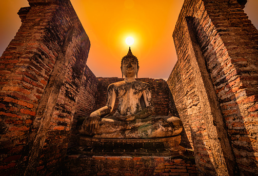 Big Buddha at sunset in Wat Mahathat temple, Sukhothai Historical Park, Thailand.