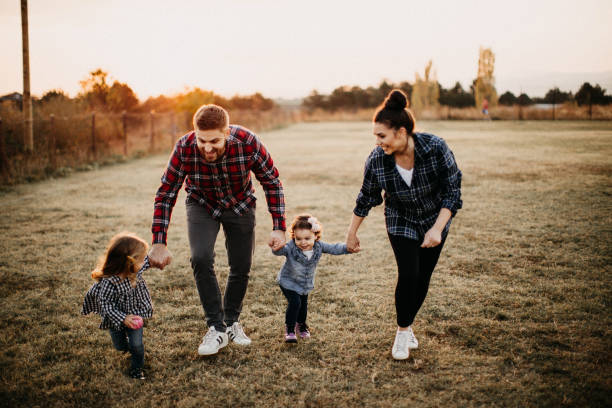 Kids plaing in meadow with parents Parents carrying kids, playing on meadow life insurance stock pictures, royalty-free photos & images