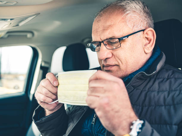 istock COVID-19, Mature man putting on disposable face mask 1212998018
