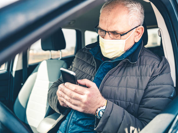 istock COVID-19, Mature man wearing disposable face mask using mobile phone 1212998131