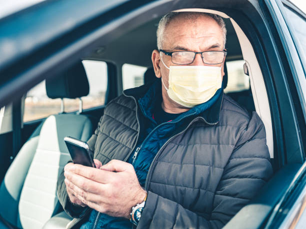 istock COVID-19, Mature man wearing disposable face mask using mobile phone 1213000030