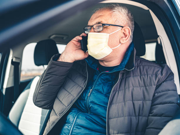 istock COVID-19, Mature man wearing disposable face mask using mobile phone 1213000068