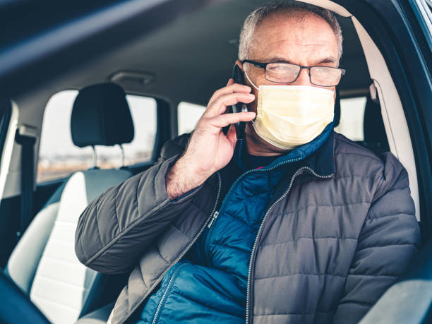 istock COVID-19, Mature man wearing disposable face mask using mobile phone 1213000588