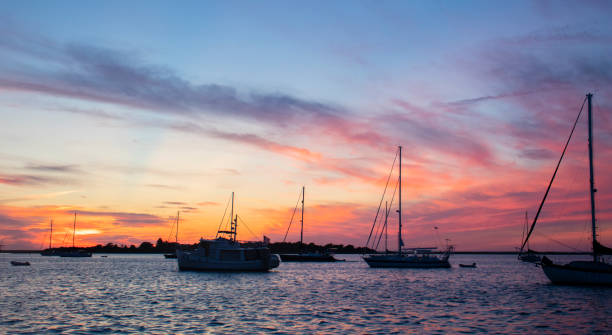 segelboote, die im block island harbor vor anker liegen, sitzen friedlich, wenn die sonne untergeht. - sailboat sunset nautical vessel sun stock-fotos und bilder