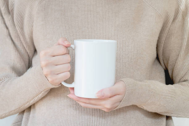 istock Mug mockup. Women's hands holding mug with blank space for your text or promotional content. 1213003855