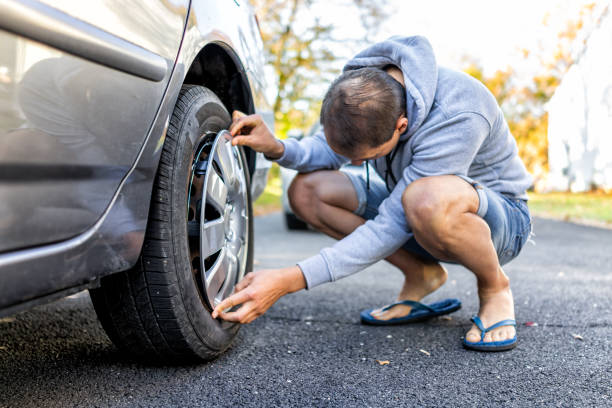 istock Tire wheel with missing cap cover on parked car with man replacing hubcap with new shiny metal outside 1213006490