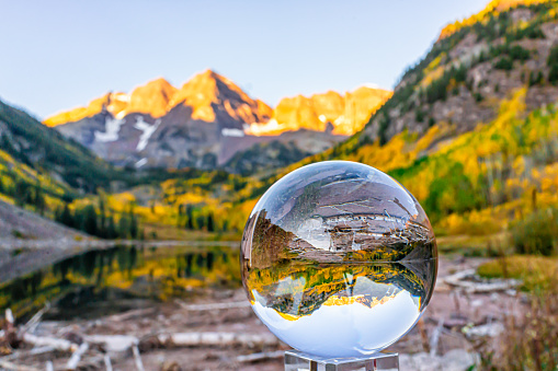 Maroon Bells lake at sunrise with crystal ball reflection in Aspen, Colorado with rocky mountain peak and snow in October 2019 autumn and vibrant trees