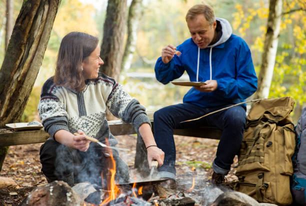 istock Man and woman making pancakes on campfire 1213007144
