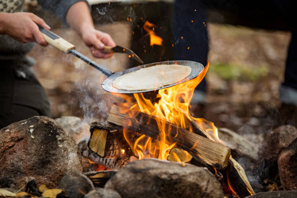 Man and woman making pancakes on campfire