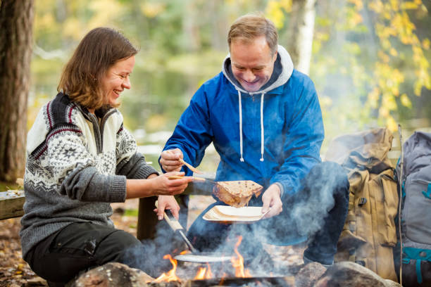 istock Man and woman making pancakes on campfire 1213007961