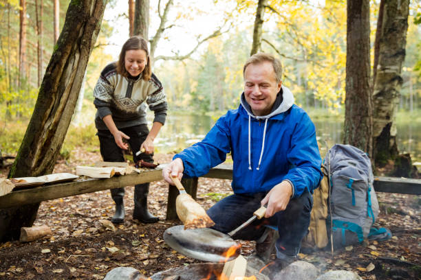 istock Man and woman making pancakes on campfire 1213008451