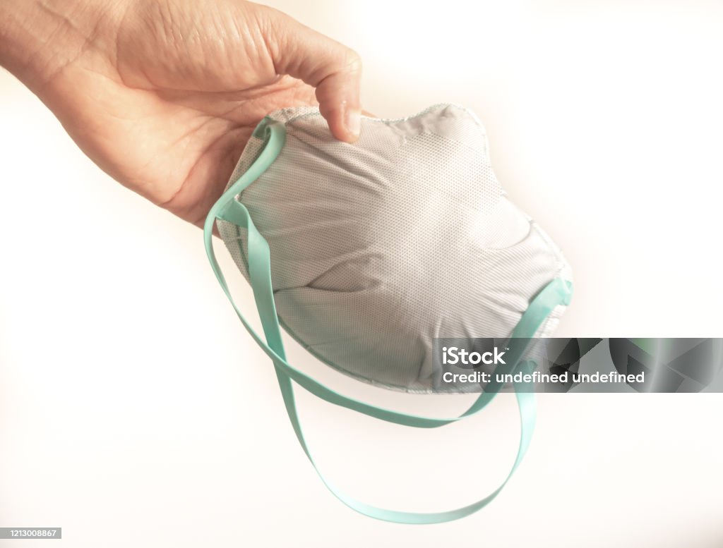 Person hand holds a fpp3 mask isolated on white. Masks needed for emergency coronavirus covid 19 Adult Stock Photo