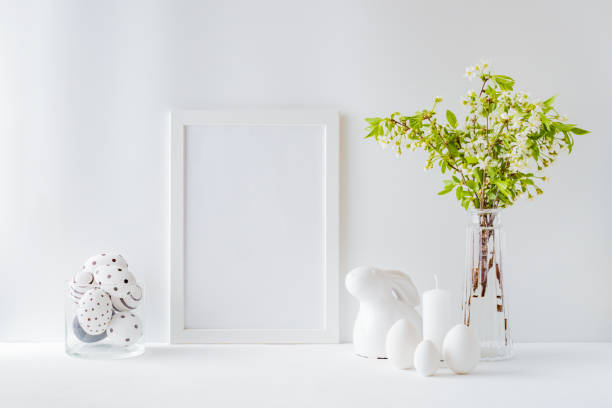 istock Home interior with easter decor. Mockup with a white frame and spring flowers in a vases on a light background 1213009570