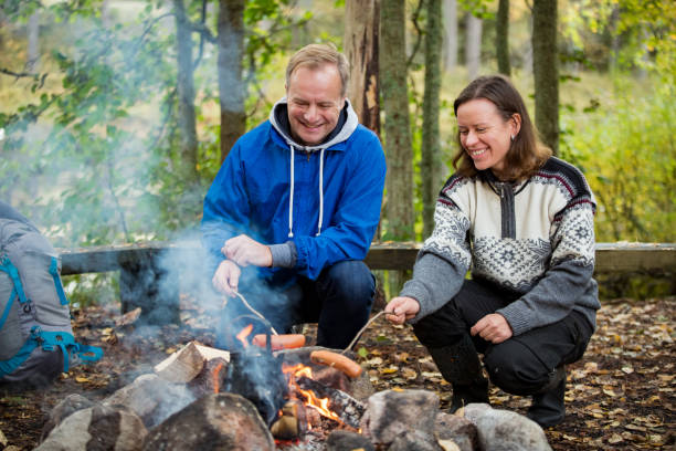 istock Man and woman roasting on campfire in forest 1213010527