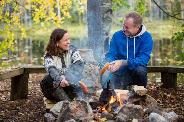 istock Man and woman roasting on campfire in forest 1213010627