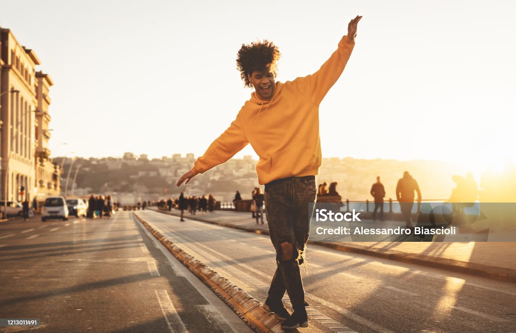 Afro American man having fun walking in city center - Happy young guy enjoying time a sunset outdoor - Millennial generation lifestyle and positive people attitude concept Dancing Stock Photo