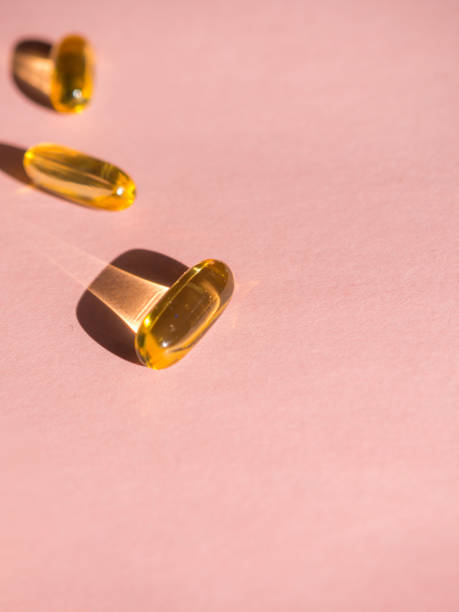 istock Oil yellow capsules on pink background 1213011722