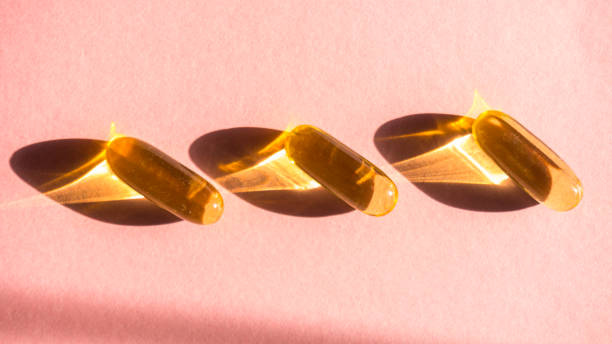 istock Oil yellow capsules on pink background 1213011911