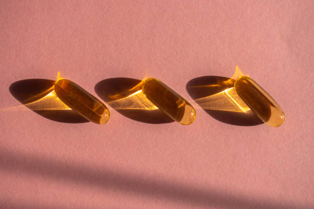 istock Oil yellow capsules on pink background 1213012259