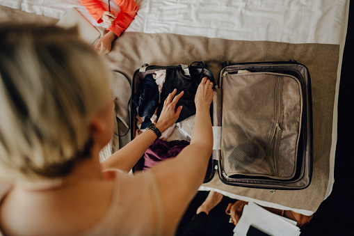 Photo of a businesswoman packing up her suitcase, while on business trip with her kids