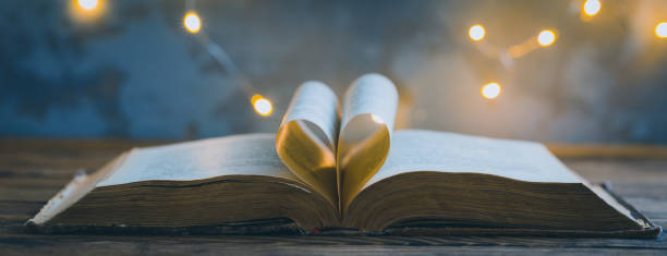 istock Old opened book, heart shaped paper sheets, dark background with stars toned vintage selective focus 1213023596