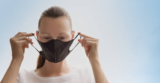 istock Woman putting on protective face mask. 1213023696