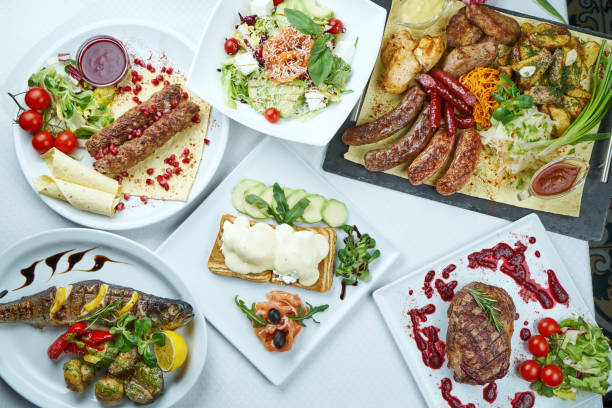 istock Dinner table with different dishes - lula kebab, chicken and pork grill, grilled sausages, beef ribeye steak, toasts with poached eggs, grilled sea bass. Top view 1213027014