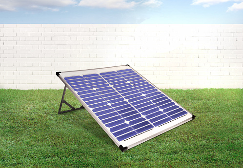 Solar panel in a backyard with green grass and brick wall