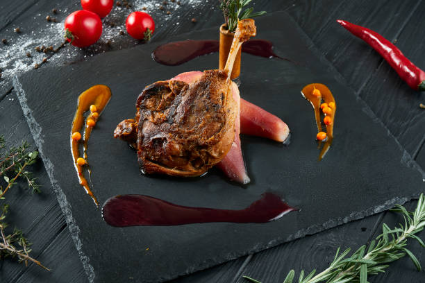 istock Duck leg confit with caramelized pear on a black slate blackboard on a black wooden background. Close up. COpy space 1213027041