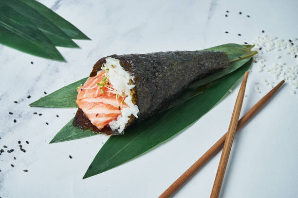 vista ravvicinata sul sushi temaki fresco e di pesce con salmone su sfondo bianco. tradizionale rotolo a mano. messa a fuoco orizzontale e selettiva - temaki food sushi salmon foto e immagini stock