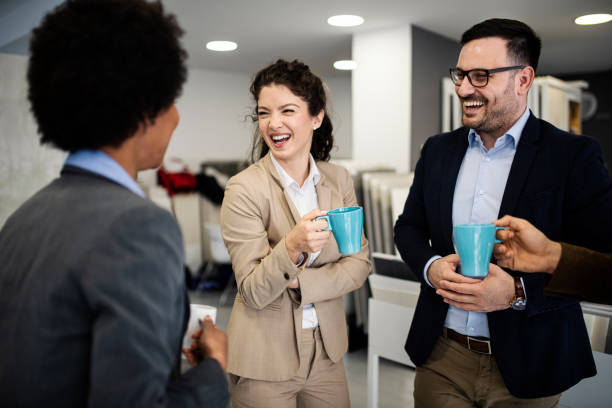 istock Group of smiling colleagues standing at workplace, chatting and drinking coffee on pause 1213027327