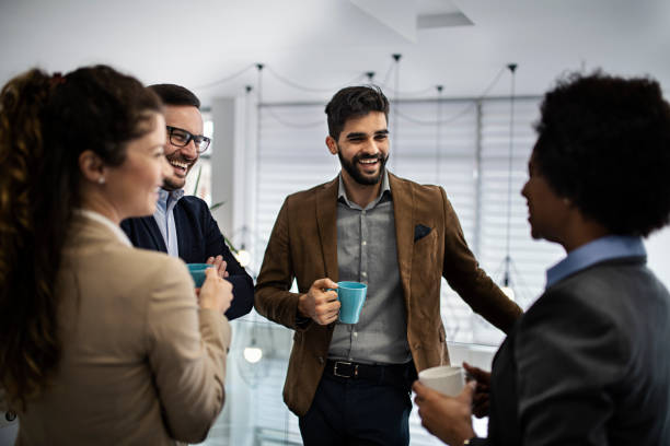 istock Group of smiling colleagues standing at workplace, chatting and drinking coffee on pause 1213027328
