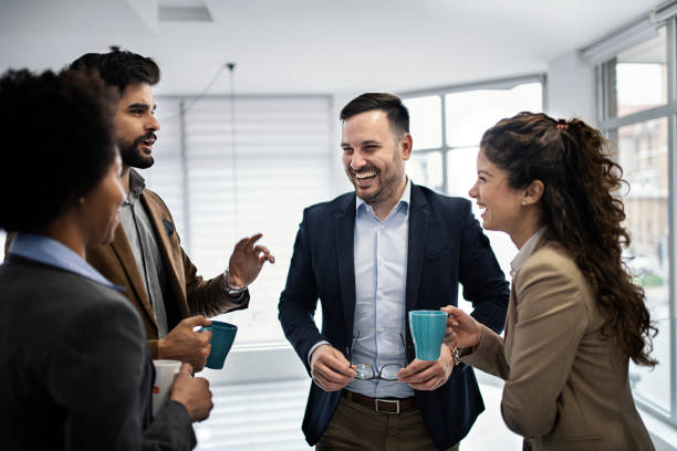 istock Group of smiling colleagues standing at workplace, chatting and drinking coffee on pause 1213027432