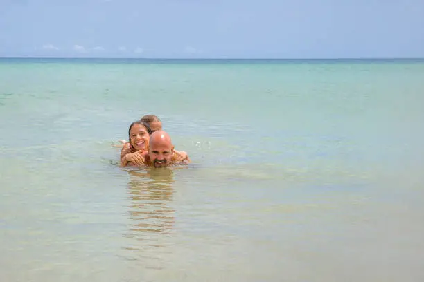 Father and daughters having fun in the sea in Porto Santos island during summer vacations