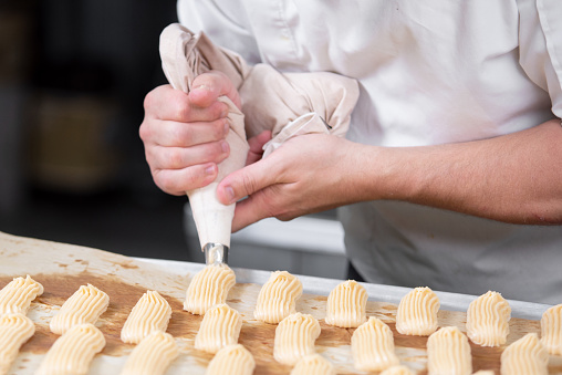 Pastry Chef with confectionary bag pouring cream.