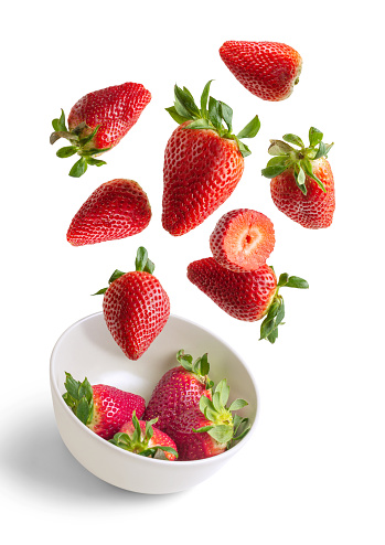 Strawberries flying in white bowl isolated from the background - red and white vertical image