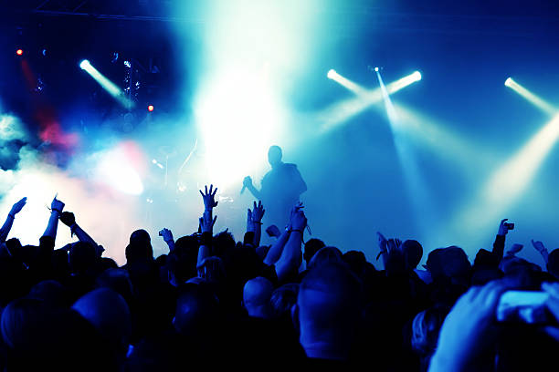 istock Crowd at concert waving hands under blue stage lights 121303035