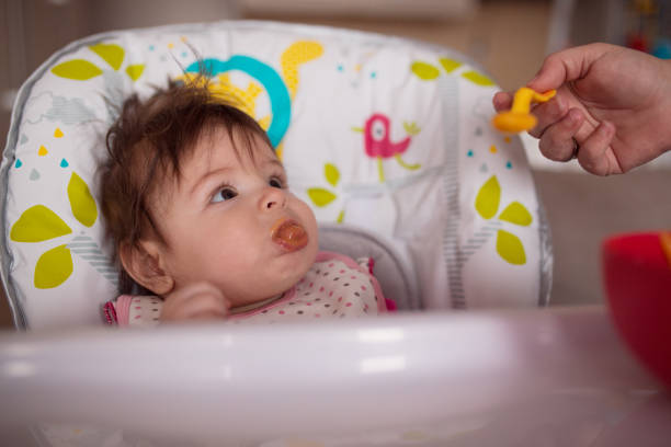 istock Baby smiling while eating in high chair 1213031093