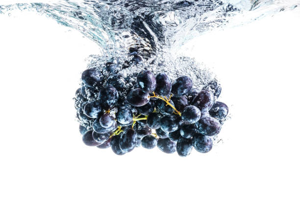 istock Bunch of red grapes splashing into crystal clear water on withe background 1213034520