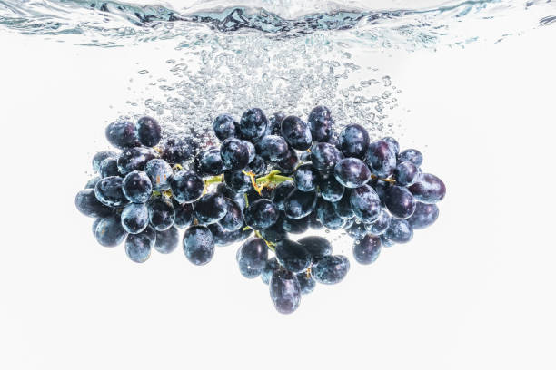 istock Bunch of red grapes splashing into crystal clear water on withe background 1213034569