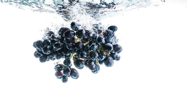 istock Bunch of red grapes splashing into crystal clear water on withe background 1213034611