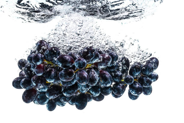 istock Bunch of red grapes splashing into crystal clear water on withe background 1213034644